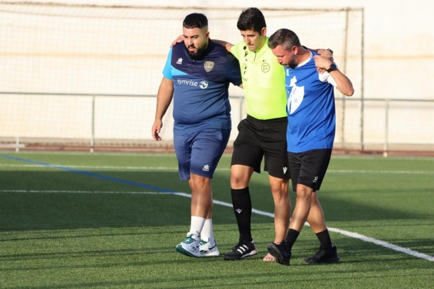 El árbitro López Romero se apoya en miembros del cuerpo técnico de Huétor Vega y Arenas tras caer lesionado (JOSÉ ANDRÉS FERNÁNDEZ / ARENAS DE ARMILLA)